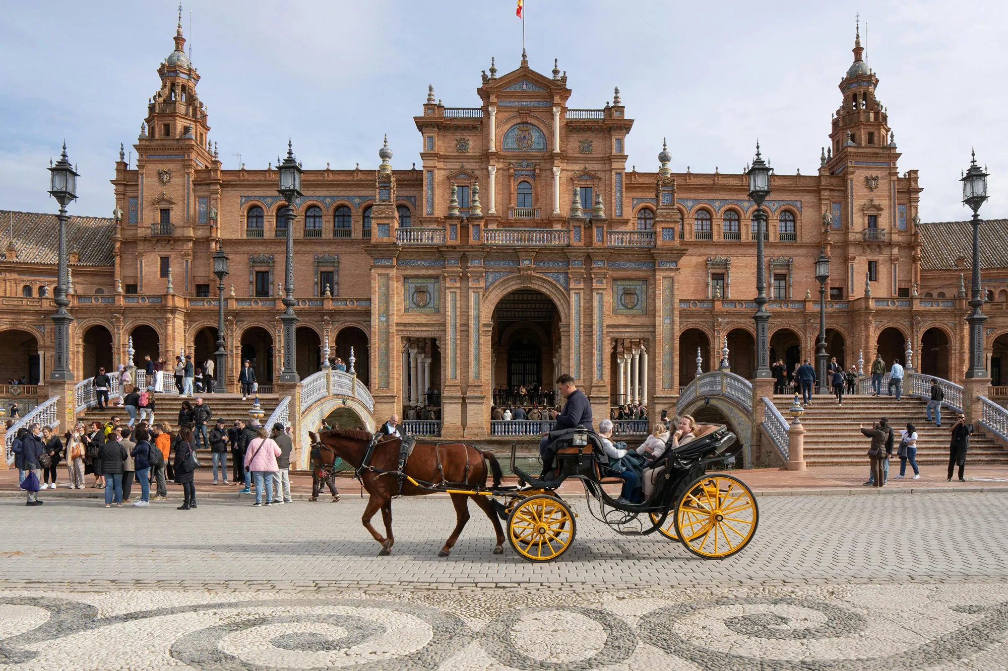 Tourists in a horse-drawn carriage at Plaza de España in Seville.