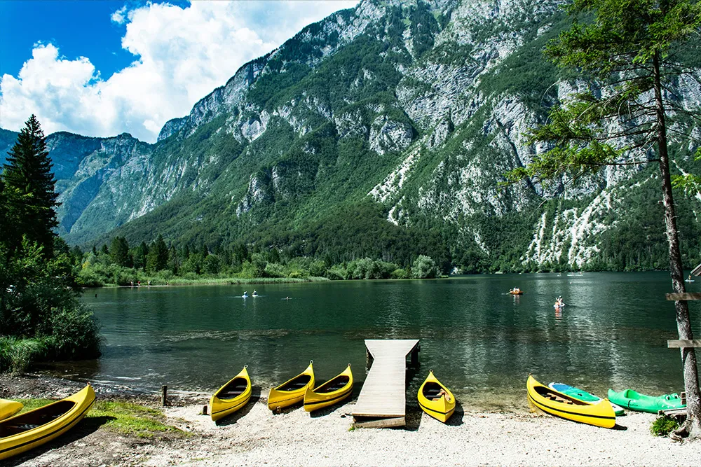 Peaceful morning view of Lake Bohinj with canoes on the water, surrounded by the Julian Alps within Triglav National Park, Slovenia