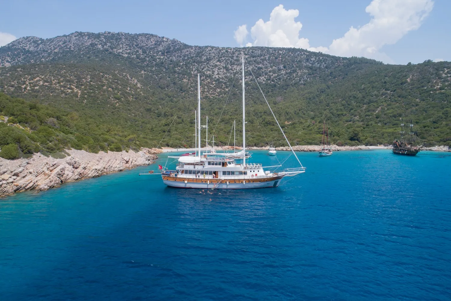 Aerial view of the Boreas yacht anchored in a crystal-clear turquoise cove in the Aegean Sea.