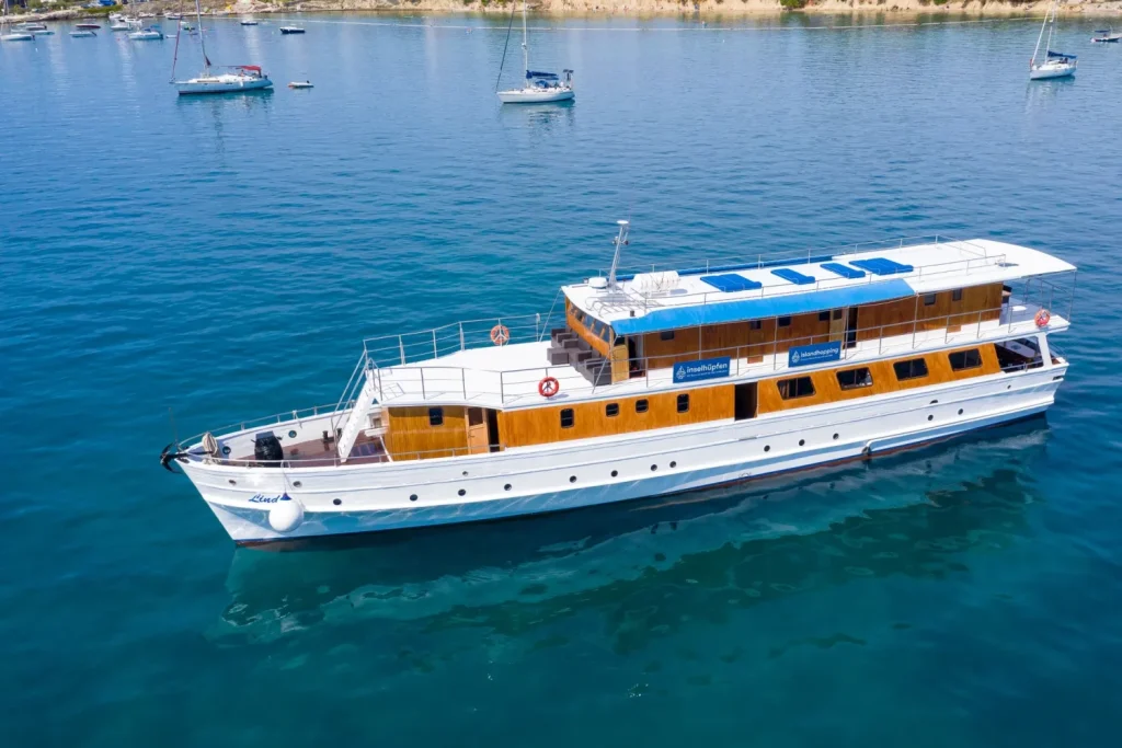 Aerial lateral view of the MS Linda motor yacht sailing on turquoise Adriatic waters near the coast.
