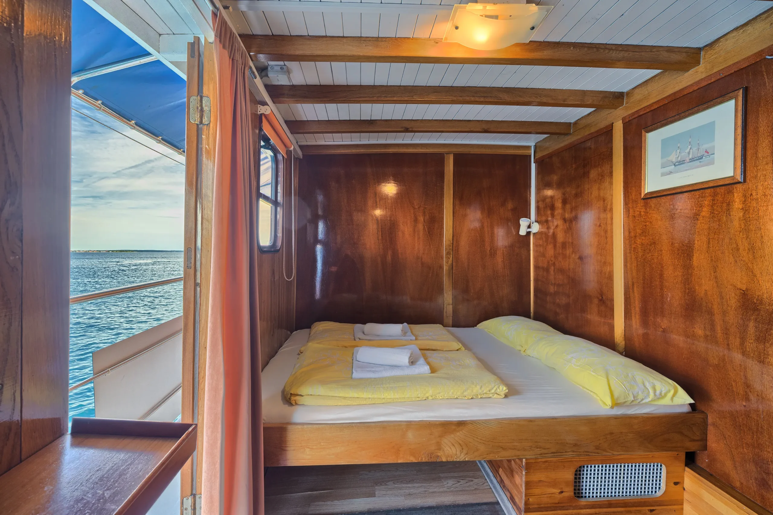 Cozy wooden cabin with a double bed and open door leading to sea views on the MS Linda boat.