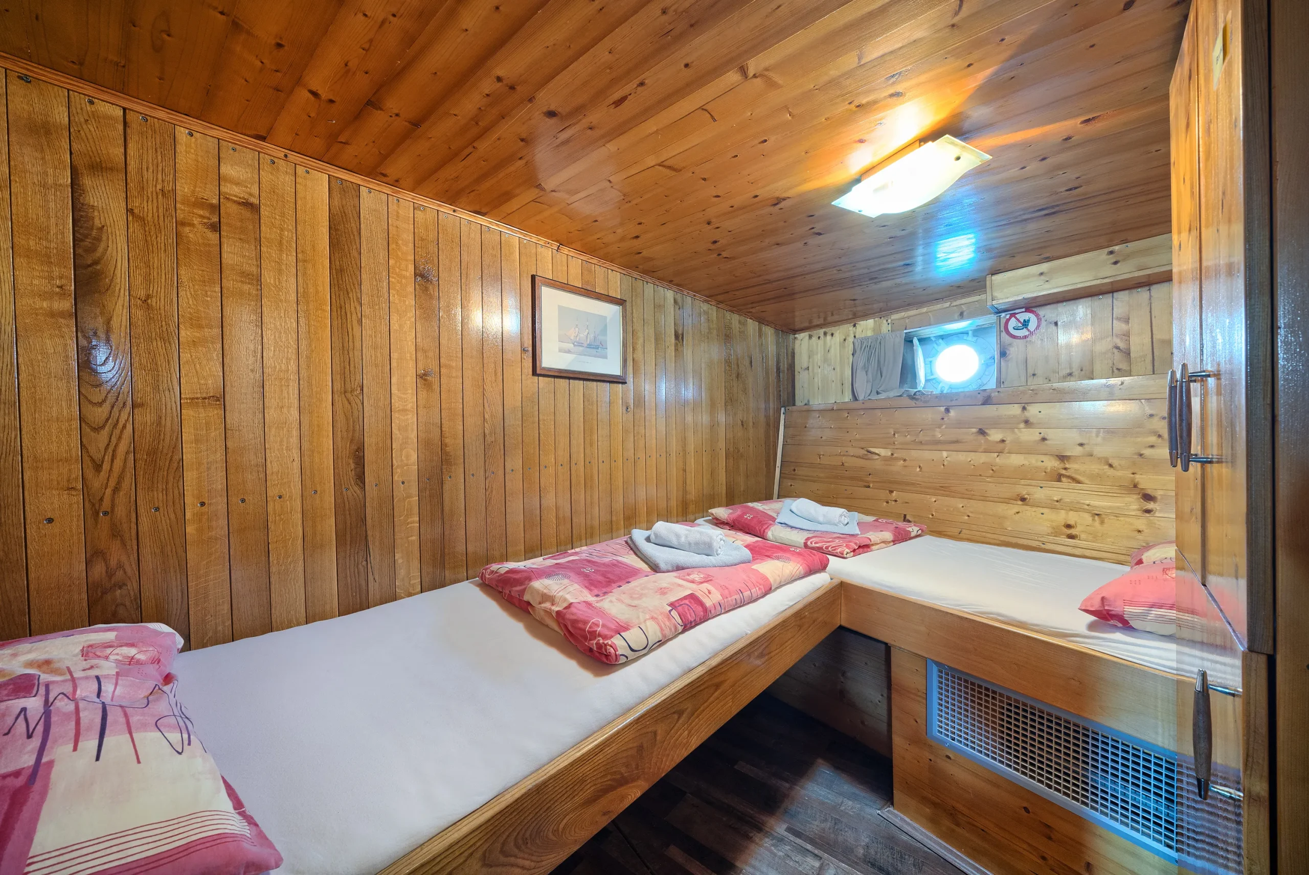 Cozy wooden twin bed cabin with fresh towels and linens on the MS Linda boat.