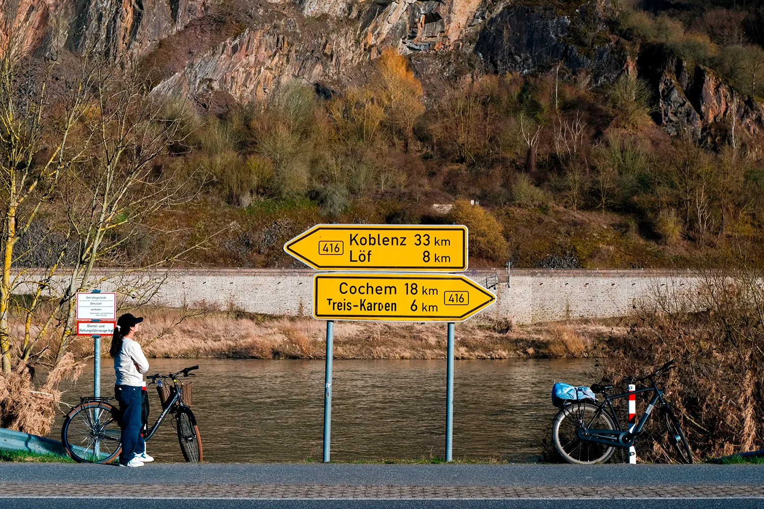 Cyclist stopping beside a road sign for Koblenz and Cochem in the German countryside