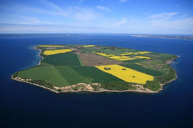 Aerial view of Ven island showing green agricultural fields, yellow rapeseed blossoms, and coastal cliffs in the Øresund strait.